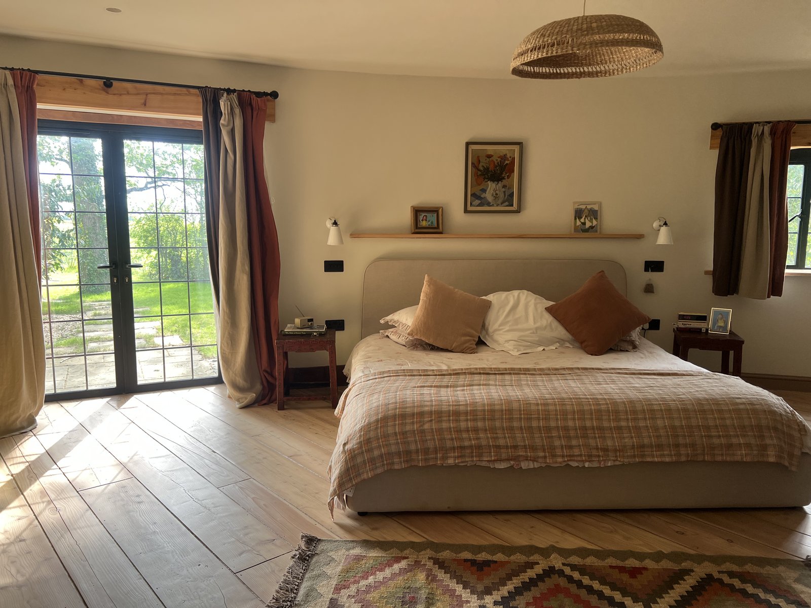Principal bedroom with French doors to the side garden, kilim rug and natural larch flooring