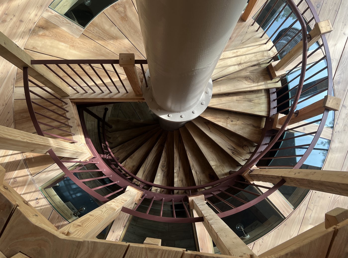 Spiral open-tread staircase wrapping around the central reclaimed-steel column