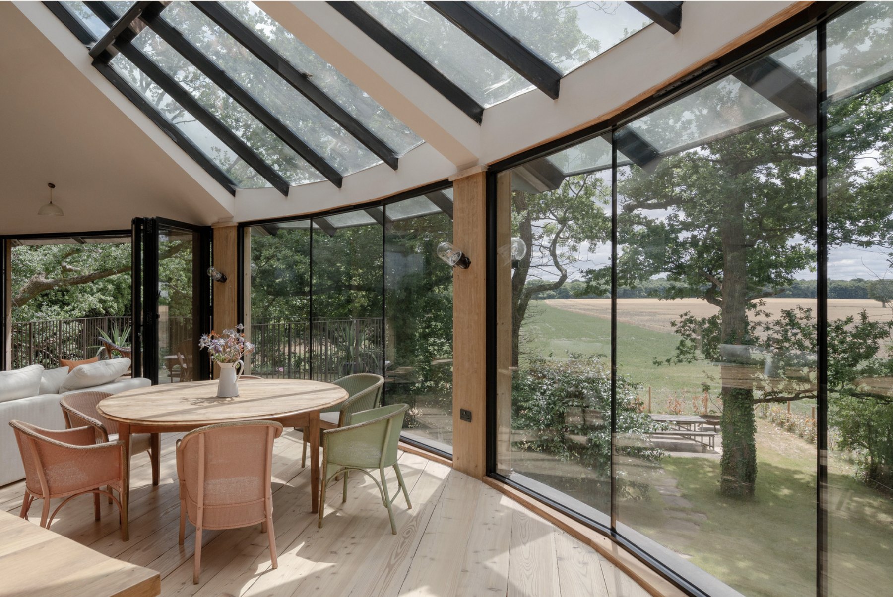 Curved glazed dining nook with floor-to-ceiling Crittall windows looking out across the wheat field