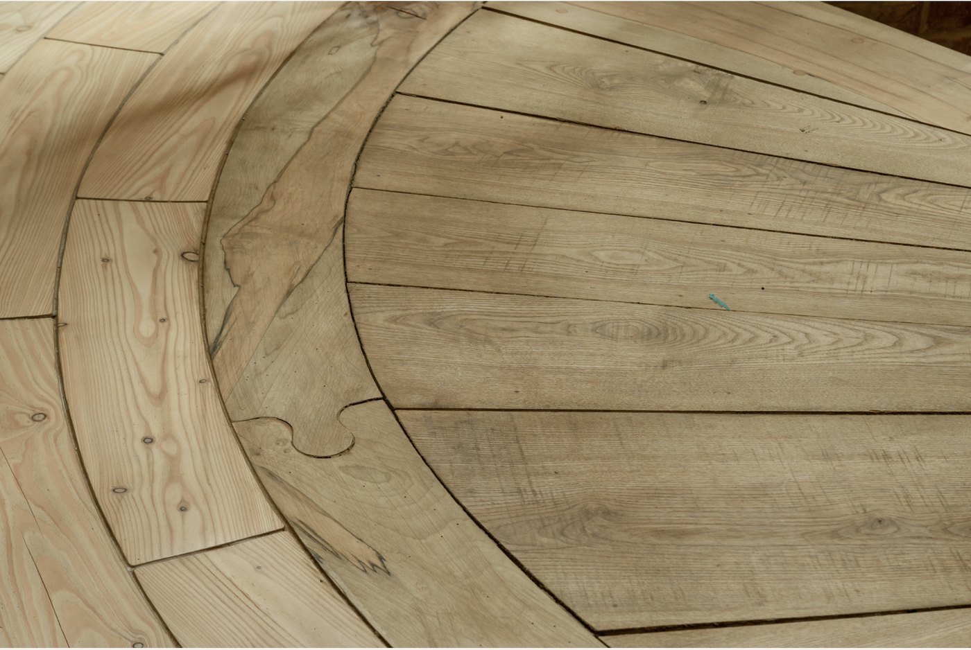 Detail of the curved solid-larch floorboards laid in concentric arcs around the central core