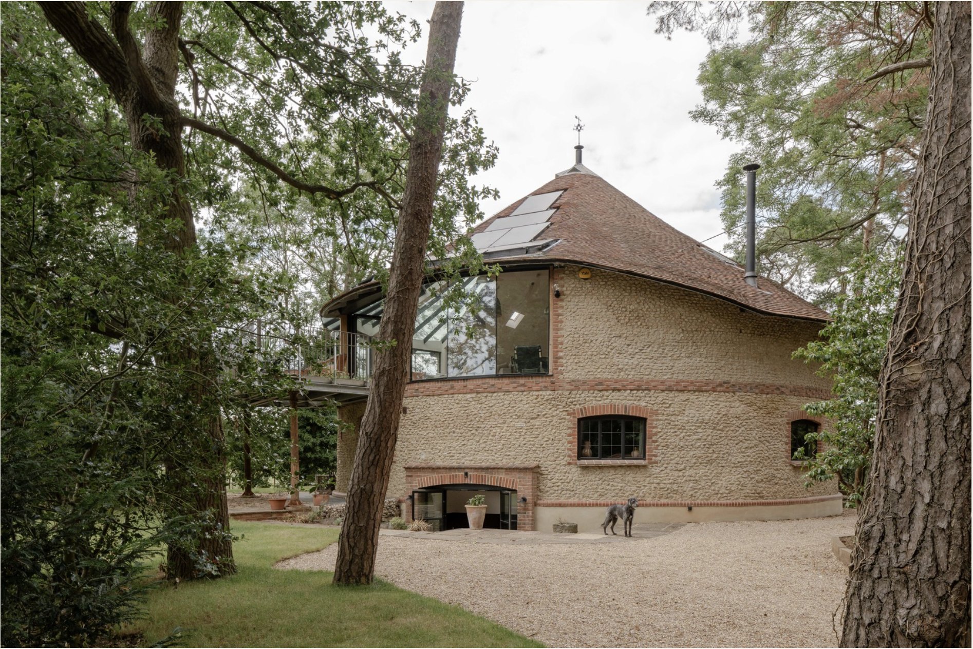 The Roundhouse — front exterior with the conical reclaimed-tile roof framed by mature trees, Old Knebworth, Hertfordshire